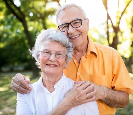 Senior man and woman holding each other outdoors