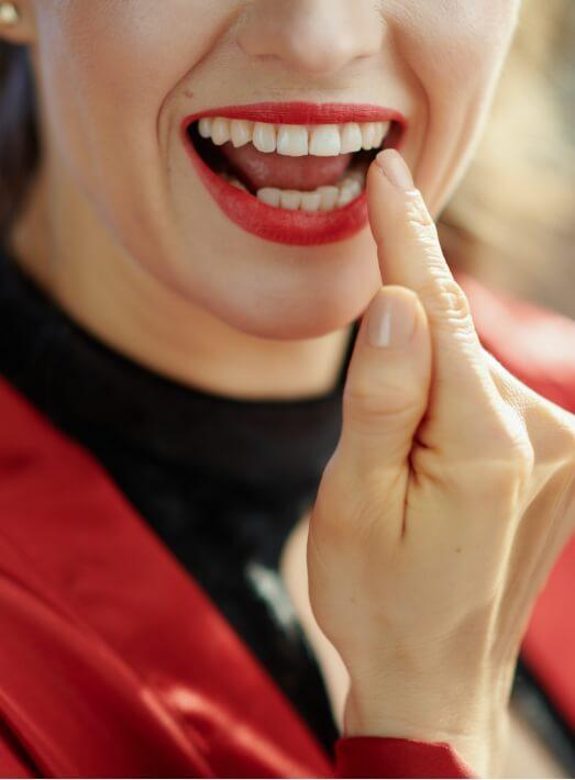 Close up of woman with red lipstick looking at her teeth in mirror