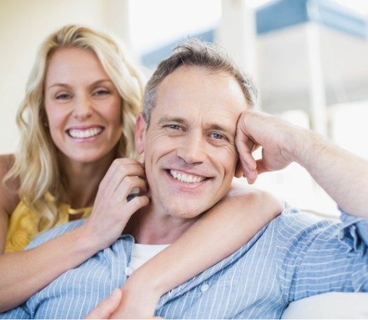 Smiling man and woman sitting on couch together
