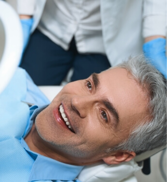 Older dental patient admiring his smile in mirror