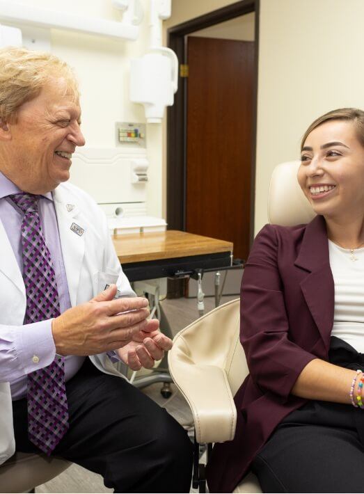 Doctor Les Latner smiling while talking to a patient in Los Angeles dental office