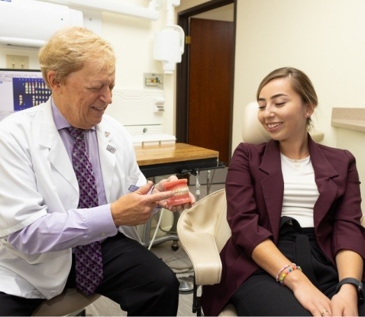 Doctor Latner showing a set of dentures to a patient
