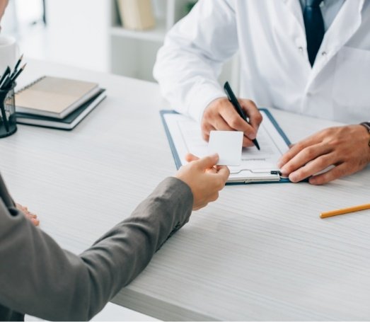 Patient handing a dental insurance card to their dentist