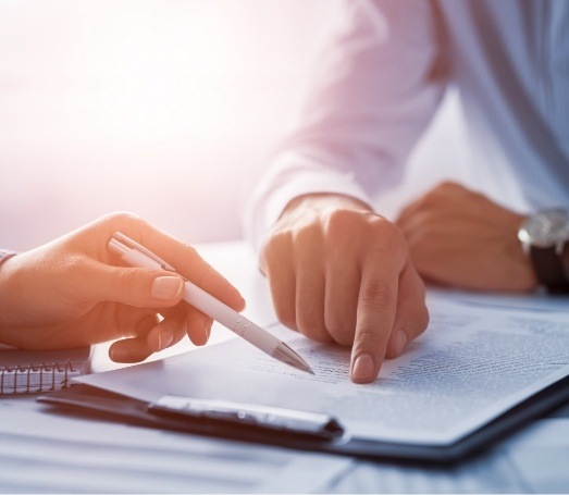 Dentist showing a patient where to sign on a form