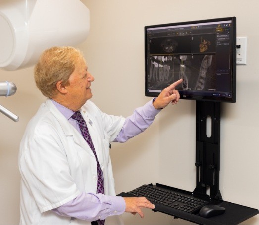 Doctor Latner pointing at computer screen showing digital dental x rays