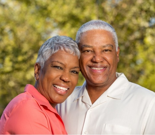 Senior man and woman hugging with trees in background