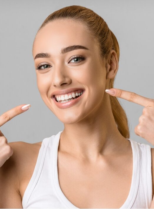 Woman pointing to her smile after cosmetic dentistry in Los Angeles