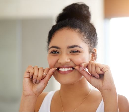 Woman smiling while flossing her teeth