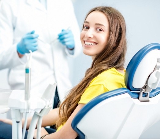 Young woman in yellow blouse grinning in dental chair