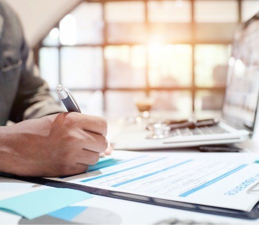 Person filling out dental insurance form on clipboard