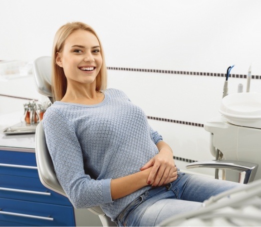 Smiling woman in light blue sweater sitting in dental chair