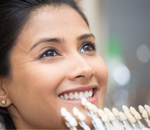Woman smiling with row of dental veneers next to her smile