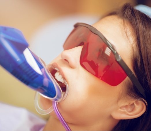 Woman getting professional teeth whitening in dental office