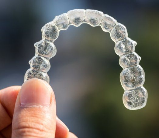 Hand holding Invisalign clear aligner