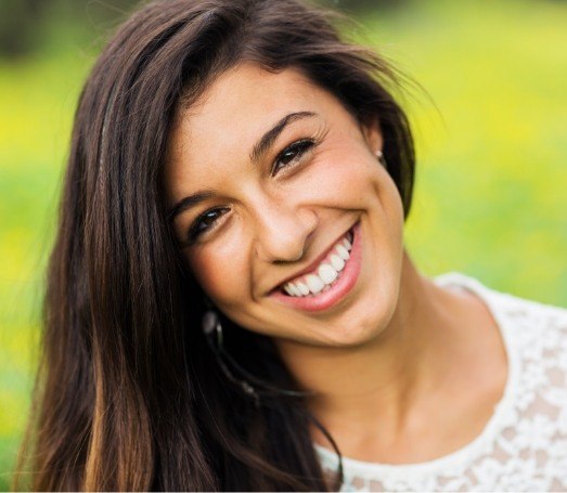 Woman with long brown hair smiling outdoors