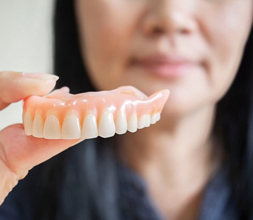 a person holding a set of dentures 