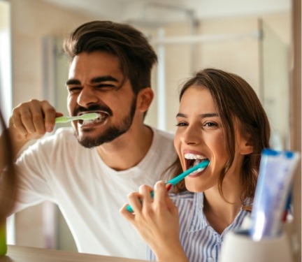 Man and woman brushing their teeth together