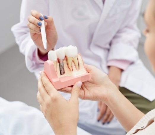 Dentist showing a dental implant model to a patient