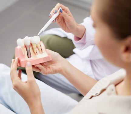 Dentist showing a model of dental implants to a patient