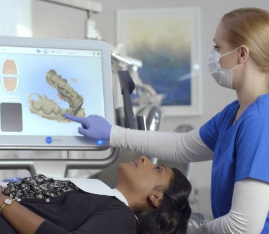 Dental team member looking at digital impressions of a patients teeth on computer screen