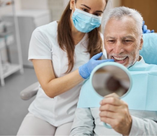 Dental team member showing a senior patient his new smile with dentures