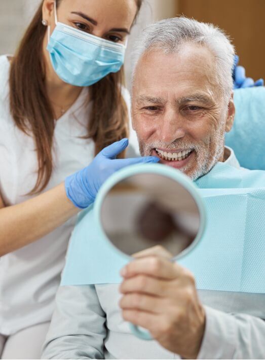 Dental assistant showing a senior patient his new smile with dentures in Los Angeles
