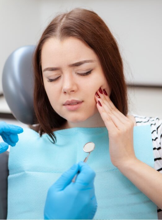 Woman holding her mouth in pain while visiting emergency dentist in Los Angeles