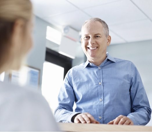 Man talking to dental team member at front desk