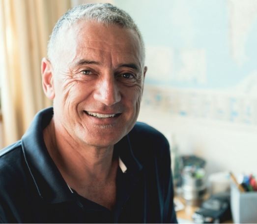 Smiling older man with world map on wall in background