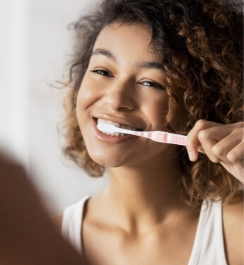 Woman smiling while brushing her teeth