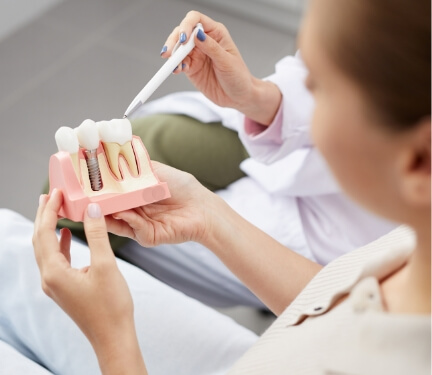 Dentist pointing to a dental implant model