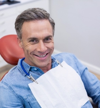 Man in denim shirt smiling in dental chair