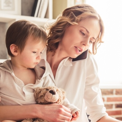 Woman talking on phone while holding toddler in one hand