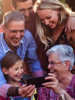 Three generations of a family looking at phone together and laughing