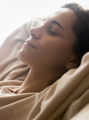 Relaxing woman leaning back with eyes closed and hands behind her head