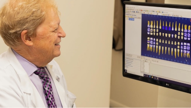 Doctor Les Latner looking at digital models of teeth on computer screen
