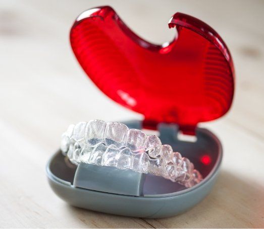 Two Invisalign aligners in their red and gray carrying case