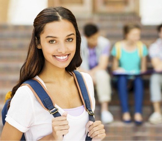 Teenage girl with backpack smiling in high school hallway