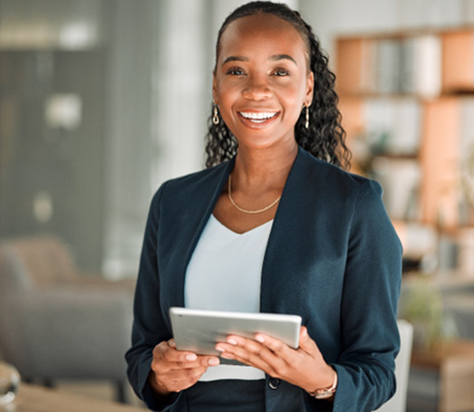Woman smiling while holding tablet in office