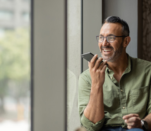 Man with glasses smiling while talking on phone