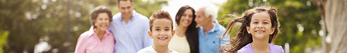 Two children running outdoors while four adults watch in background