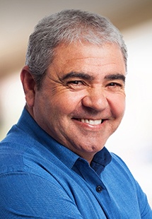 Older man in blue collared shirt smiling