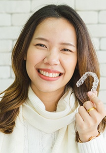 Young woman in white sweater holding clear aligner