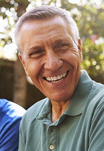 Older man in green polo shirt laughing outdoors