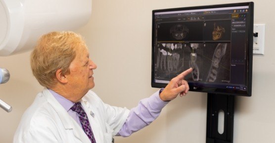 Doctor Latner pointing to computer screen showing dental x rays