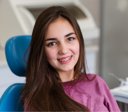 Young woman grinning and holding Invisalign clear aligner outdoors