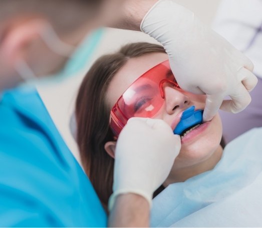 Young woman receiving fluoride treatment in dental office