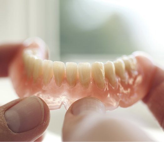 Person holding a denture in their hands