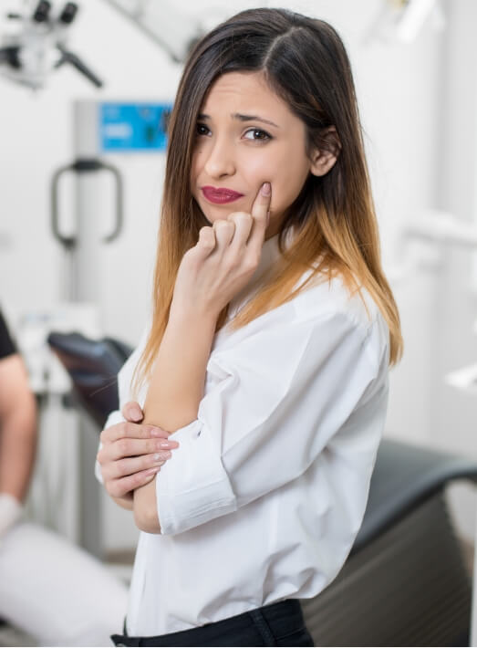 Woman pointing to hurting mouth needing root canal treatment in Los Angeles