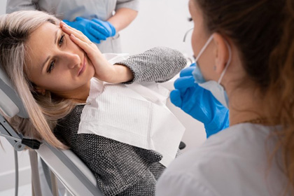 Dentist talking to female patient who is in pain 